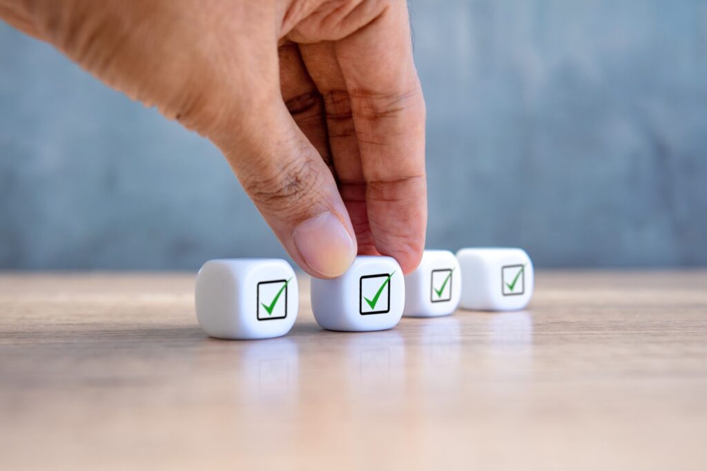 A hand is reaching for a white cube with a checkmark on it.