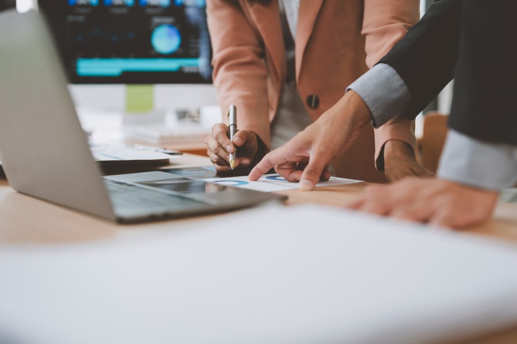 Business people analyzing statistics document, pointing and taking notes with pen
