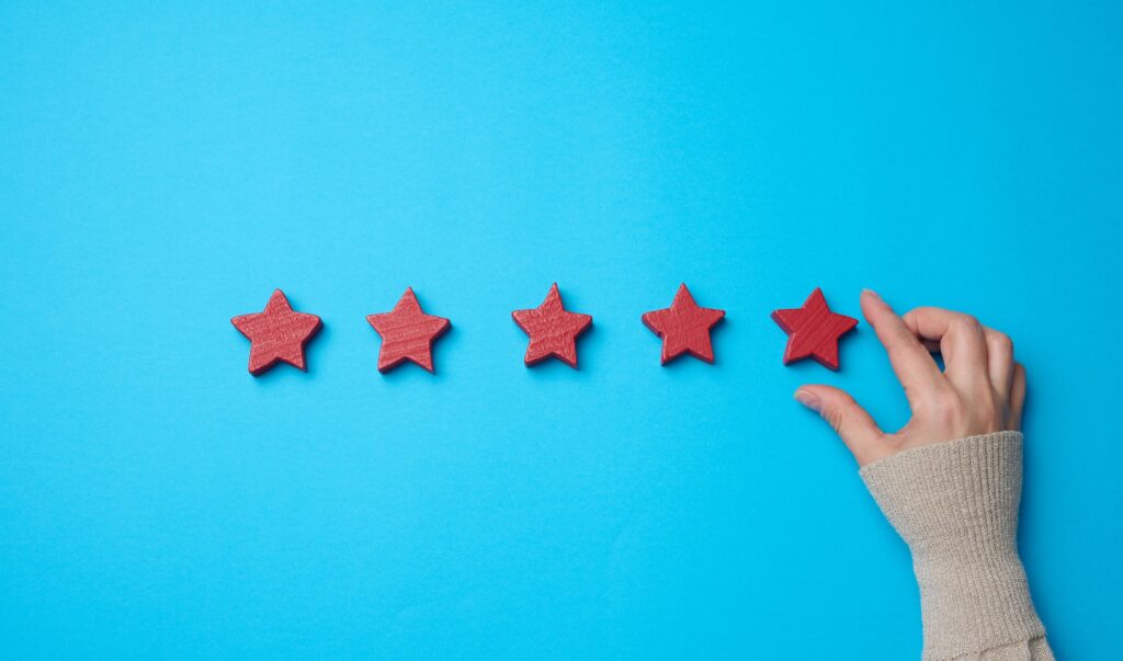 Five red stars and a hand on a blue background. Evaluation of the quality of services and goods