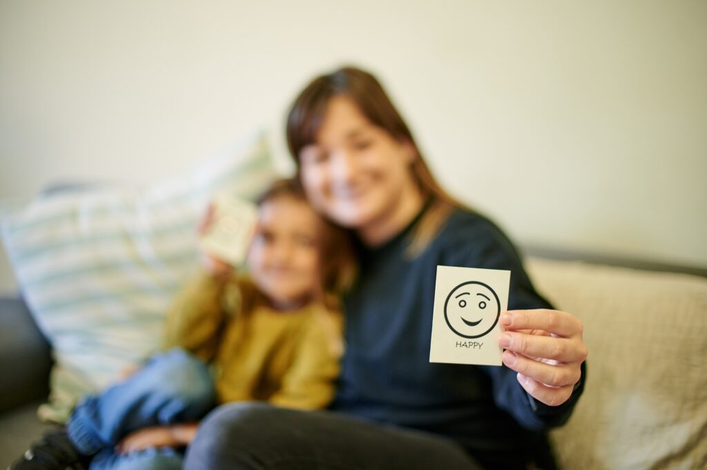 Happy, therapist and a child with an emotion card, showing reaction and feelings in therapy. Togeth