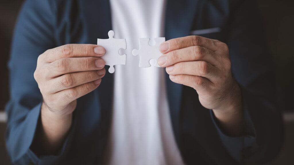 Man holding two jigsaw puzzles put together, business management concept