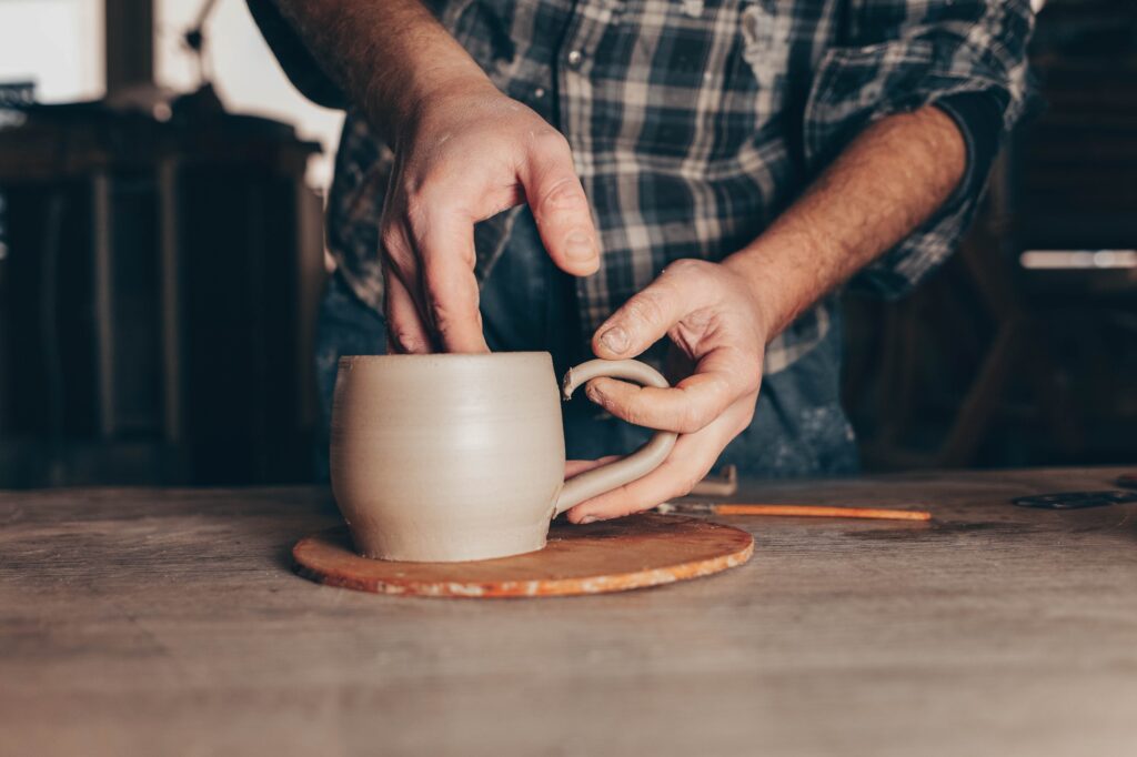 Potter glues ears to a cup. Process of creating a ceramic cup